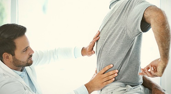 врач проводит осмотр спины пациента