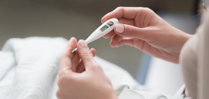 Женщина держит градусник в руках